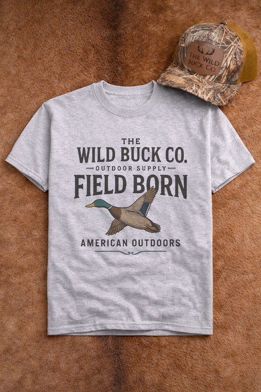 Gray t-shirt with 'The Wild Buck Co.' branding and duck graphic on a brown leather background.