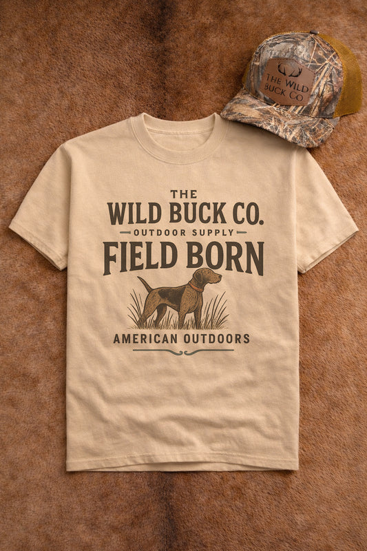 Beige t-shirt with 'The Wild Buck Co.' text and graphic, paired with a camouflage cap on a brown background.